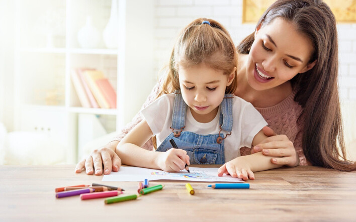 Une assistante maternelle garde une enfant et dessine avec elle