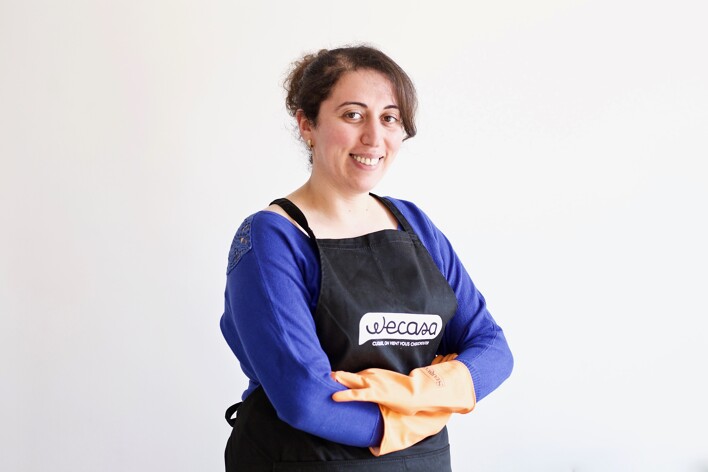 Wecasa domestic cleaner smiling and crossing her arms while wearing orange cleaning gloves 