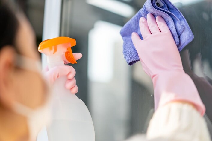 cleaner wiping window with cloth and solution