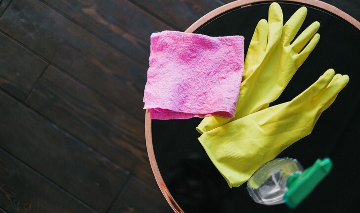 Latex gloves and bottle of cleaning product placed on a table 