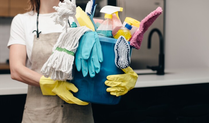 Professional cleaner has a bucket filled with cleaning products.