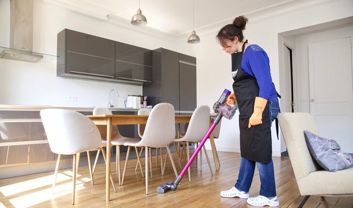 service de ménage à domicile, femme de ménage passant l'aspirateur dans le salon