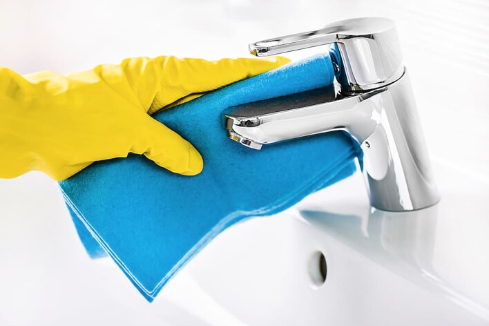 Wiping bathroom tap with cloth