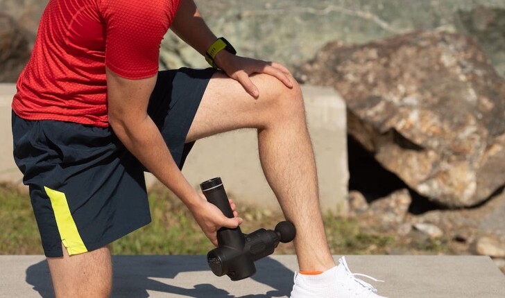 Man using massage gun on leg