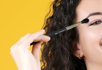 A woman is applying makeup to her face