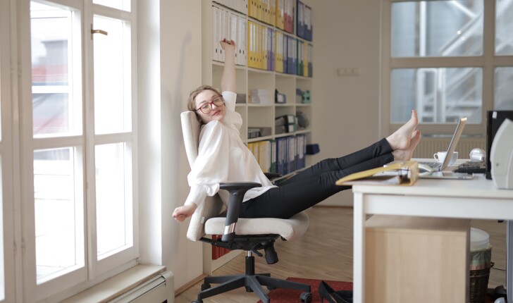 happy woman employee relaxing with feet on table in a office