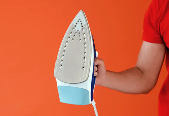 Haushaltshilfe hält ein Bügeleisen in der Hand