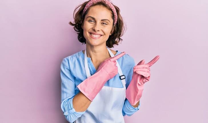 Happy part-time cleaner waring pink cleaning gloves