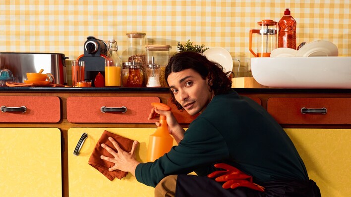 Professional cleaning man cleaning the kitchen with a red cloth and an orange product bottle